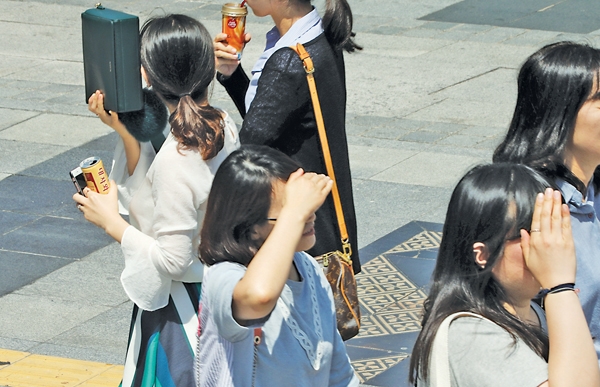 서울 시내에서 시민들이 강한 자외선을 피하기 위해 손과 가방으로 햇빛을 가리고 걸어가고 있다. 	사진=연합뉴스