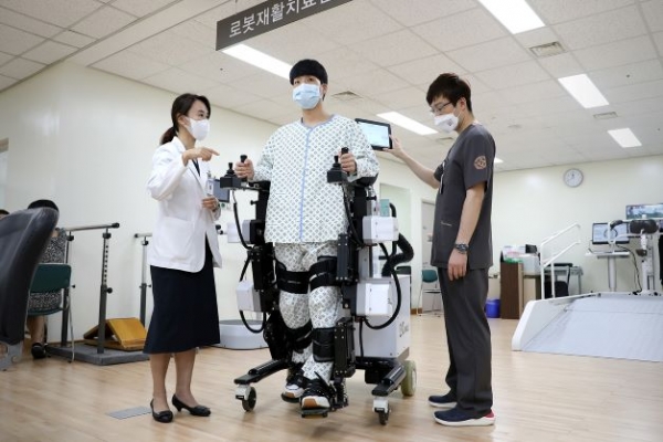 유지현 일산백병원 재활의학과 교수(왼쪽)가 환자에게 보행 로봇 치료 방법을 설명하고 있다.