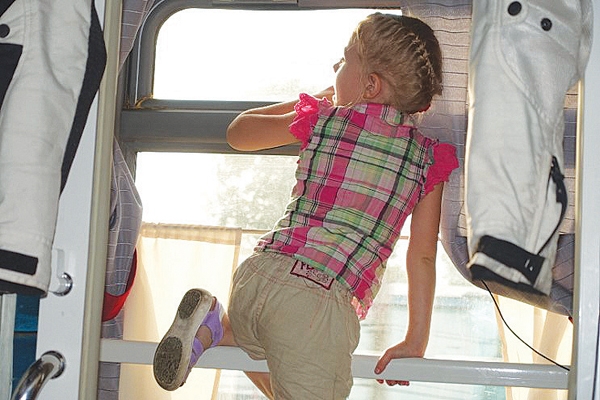 옆 객실의 아이가 기차여행이 지루한 듯 구조물에 걸터앉아 밖을 보고 있다.
